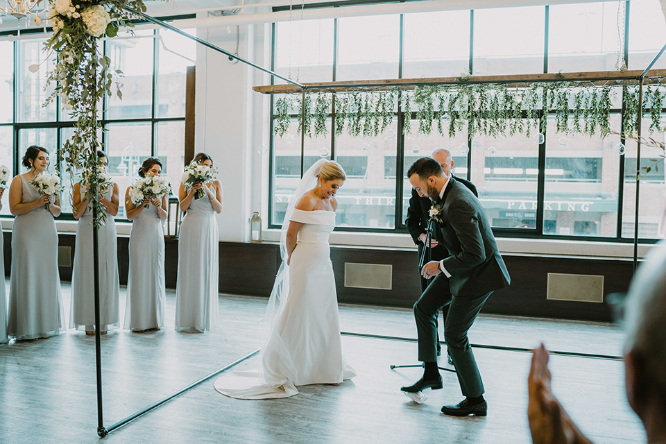  bride in an off the shoulder modern gown and the groom in a charcoal shawl lapel tuxedo 