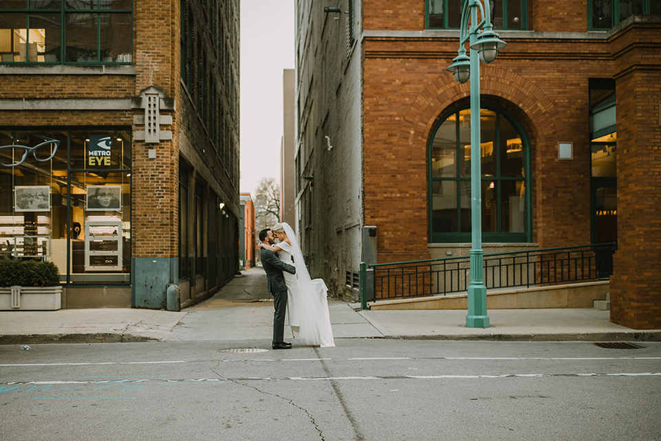  bride in an off the shoulder modern gown and the groom in a charcoal shawl lapel tuxedo 