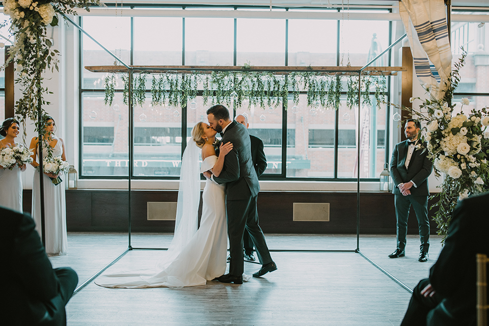  bride in an off the shoulder modern gown and the groom in a charcoal shawl lapel tuxedo 