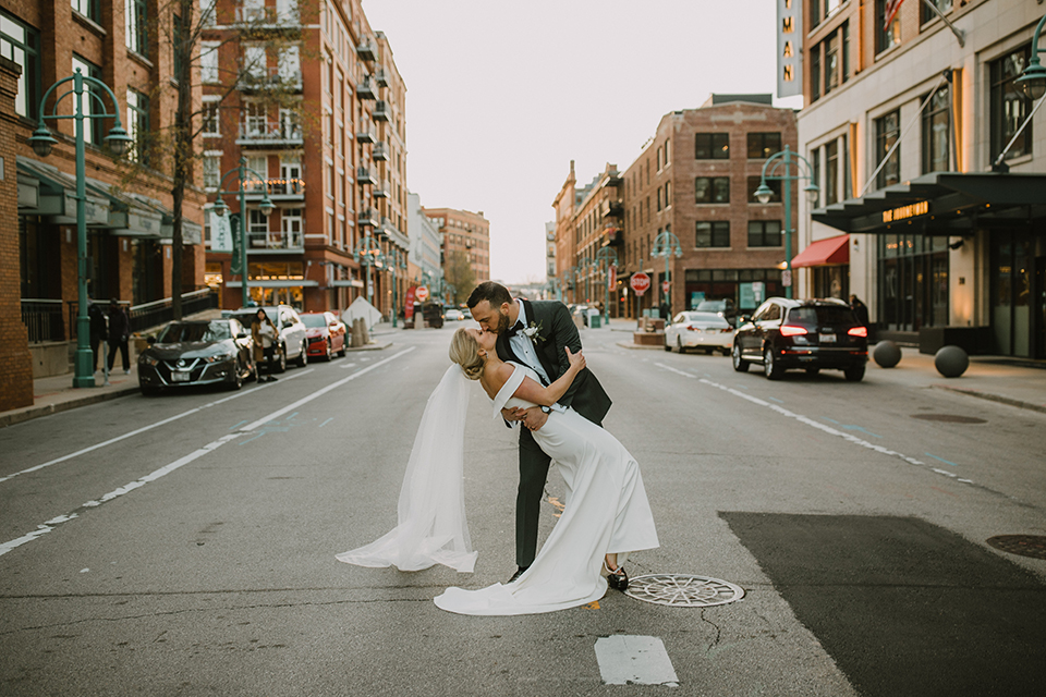  bride in an off the shoulder modern gown and the groom in a charcoal shawl lapel tuxedo 