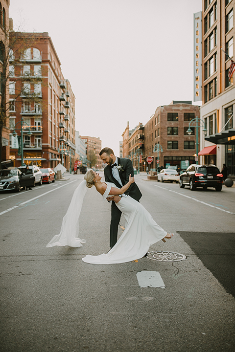  bride in an off the shoulder modern gown and the groom in a charcoal shawl lapel tuxedo 