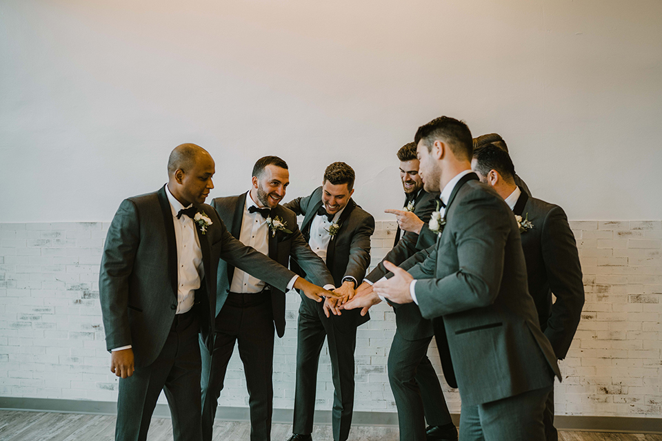  bride in an off the shoulder modern gown and the groom in a charcoal shawl lapel tuxedo 