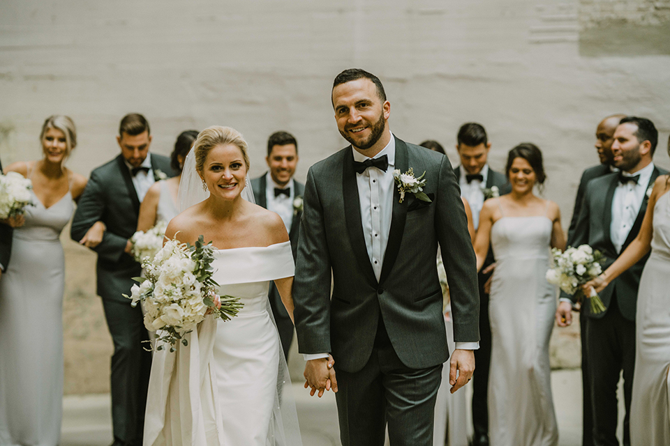  bride in an off the shoulder modern gown and the groom in a charcoal shawl lapel tuxedo 