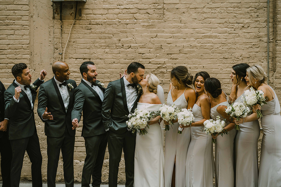  bride in an off the shoulder modern gown and the groom in a charcoal shawl lapel tuxedo 