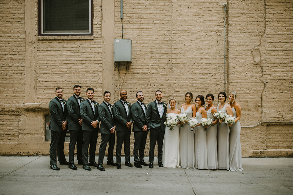  bride in an off the shoulder modern gown and the groom in a charcoal shawl lapel tuxedo 