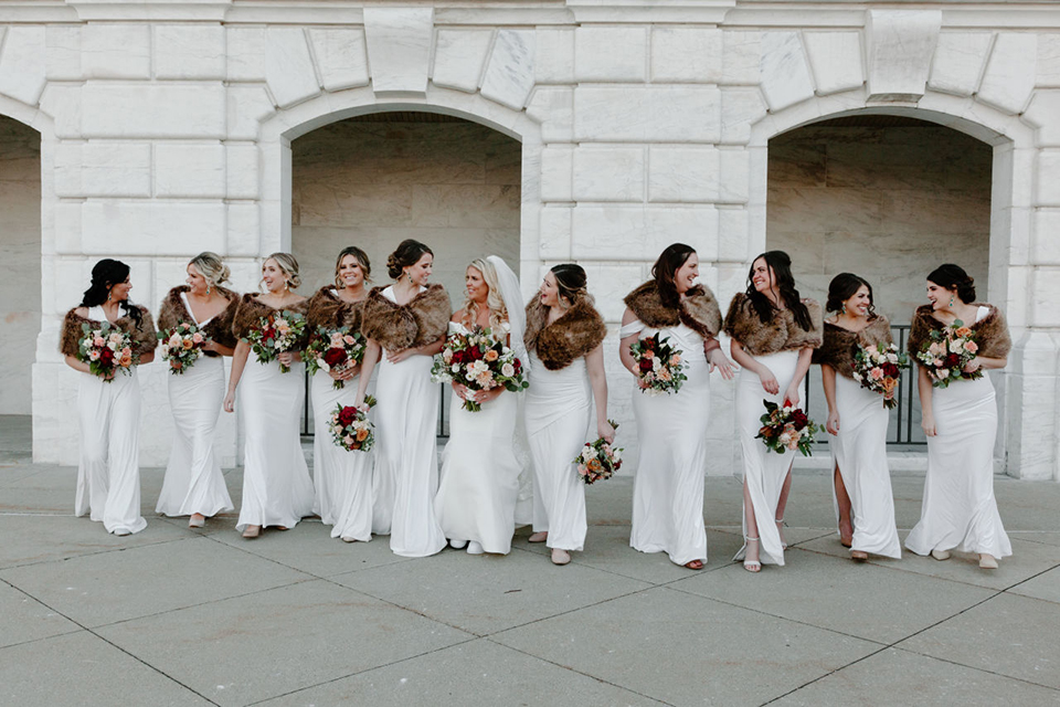  bride in a trumpet style gown and the groom in a green suit, the groomsmen in caramel notch lapel suits and the bridesmaids in ivory gowns 