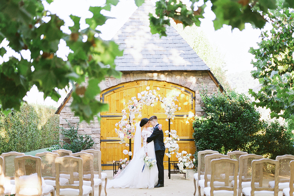  a gold and navy wedding at kestrel park with the groom in a navy tuxedo and the bride in a lace ballgown with long sleeves 