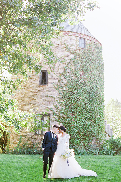  a gold and navy wedding at kestrel park with the groom in a navy tuxedo and the bride in a lace ballgown with long sleeves 