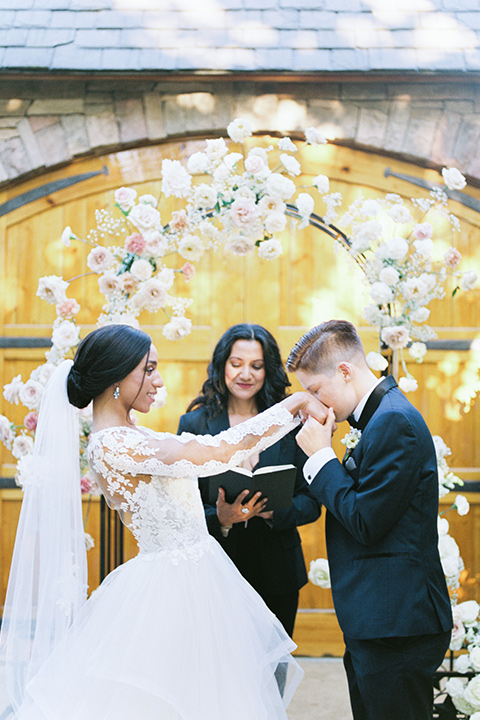  a gold and navy wedding at kestrel park with the groom in a navy tuxedo and the bride in a lace ballgown with long sleeves 