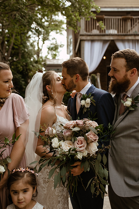  a romantic church wedding with the groom and groomsmen in cobalt blue suit and the bridesmaids in blush and the bride in a lace fitted gown 