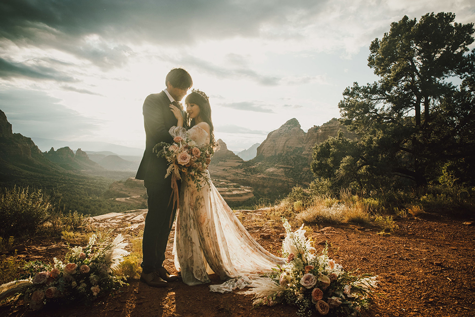  Sedona elopement with bohemian flare – the groom in a green suit and the bride in a boho dress and jean jacket 