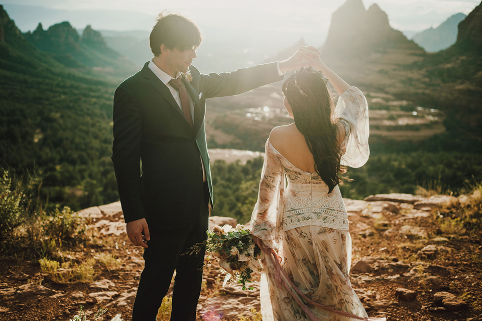  Sedona elopement with bohemian flare – the groom in a green suit and the bride in a boho dress and jean jacket 