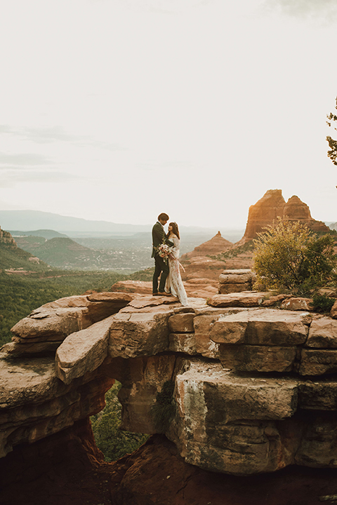  Sedona elopement with bohemian flare – the groom in a green suit and the bride in a boho dress and jean jacket 