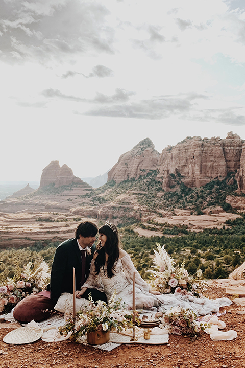  Sedona elopement with bohemian flare – the groom in a green suit and the bride in a boho dress and jean jacket 