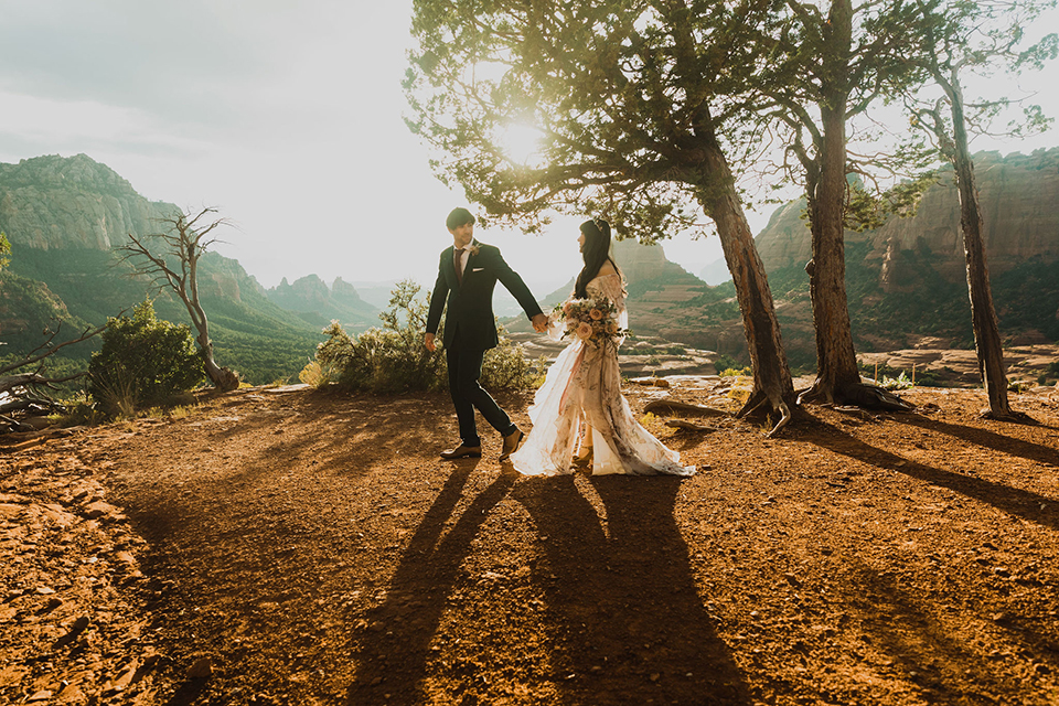  Sedona elopement with bohemian flare – the groom in a green suit and the bride in a boho dress and jean jacket 