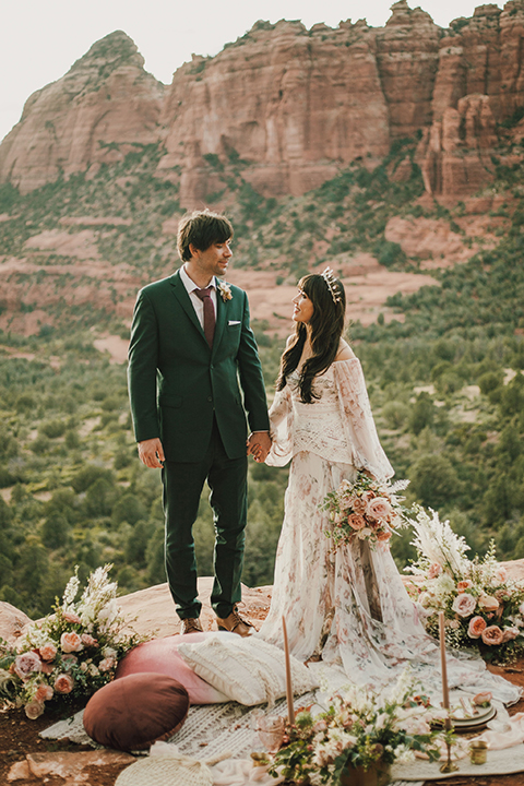  Sedona elopement with bohemian flare – the groom in a green suit and the bride in a boho dress and jean jacket 