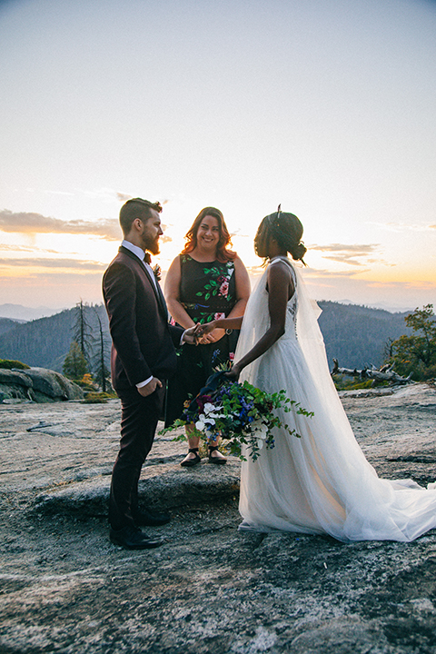  boho wedding with the ceremony inside and the reception on the cliffs overlooking the ocean and the bride in a finged gown and the groom in a tan suit 