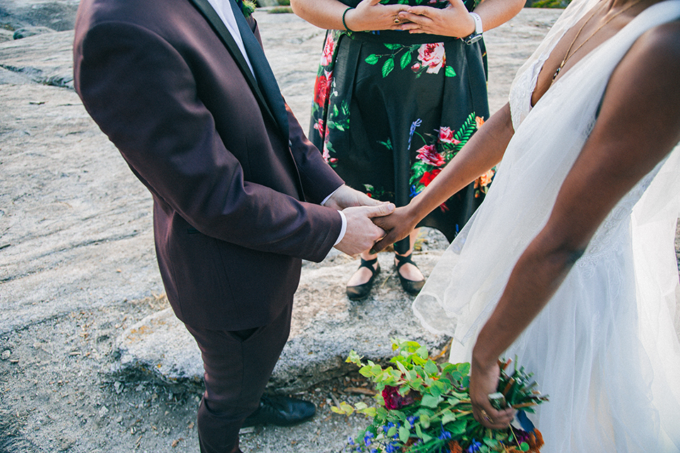  boho wedding with the ceremony inside and the reception on the cliffs overlooking the ocean and the bride in a finged gown and the groom in a tan suit 