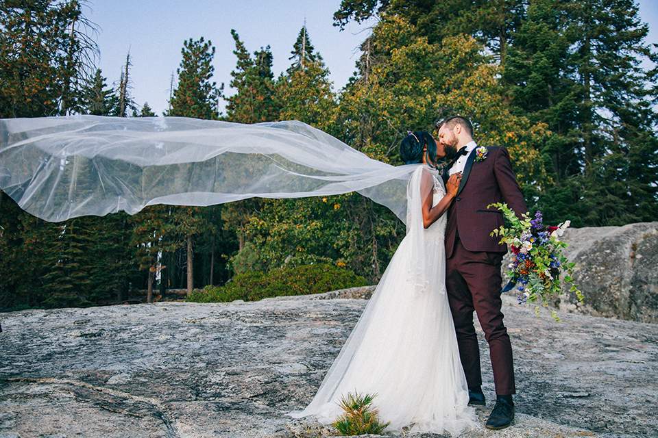  boho wedding with the ceremony inside and the reception on the cliffs overlooking the ocean and the bride in a finged gown and the groom in a tan suit 