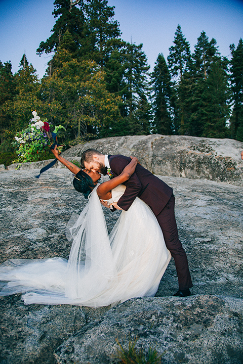  boho wedding with the ceremony inside and the reception on the cliffs overlooking the ocean and the bride in a finged gown and the groom in a tan suit 