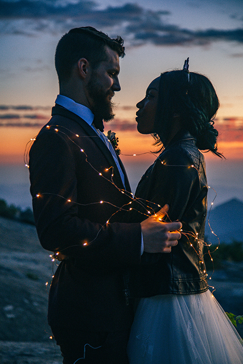  boho wedding with the ceremony inside and the reception on the cliffs overlooking the ocean and the bride in a finged gown and the groom in a tan suit 