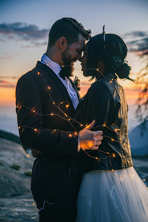  boho wedding with the ceremony inside and the reception on the cliffs overlooking the ocean and the bride in a finged gown and the groom in a tan suit 