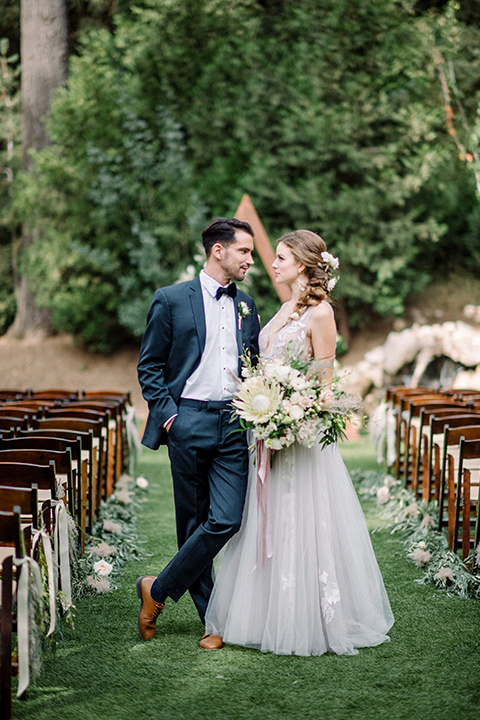  garden themed wedding with the bride in a light lilac colored gown and the groom in a navy suit with lots of wedding day flowers