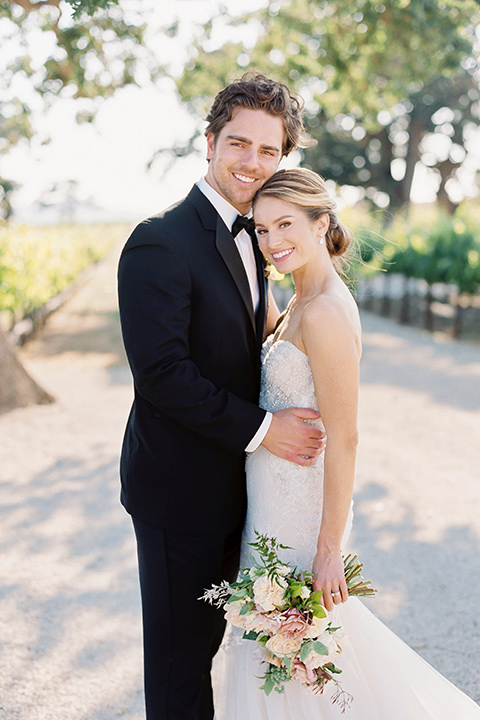  bride in a trumpet gown and her hair in a bun and the groom in a classic black tuxedo and black bow tie 