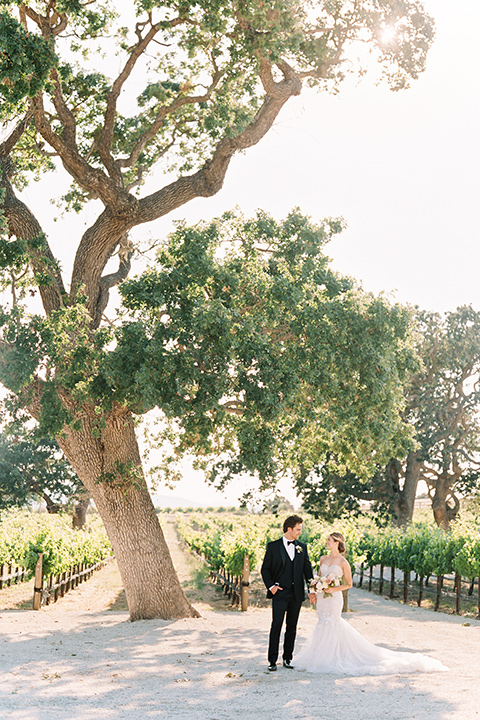  bride in a trumpet gown and her hair in a bun and the groom in a classic black tuxedo and black bow tie 