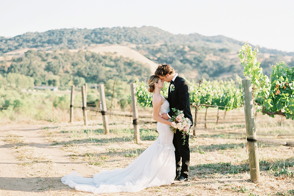  bride in a trumpet gown and her hair in a bun and the groom in a classic black tuxedo and black bow tie 