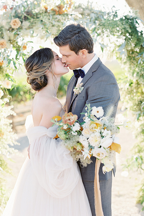  wedding at sunstone winery with romantic details and the groom in a café brown suit and the bride in a flowing ballgown with billowing sleeves