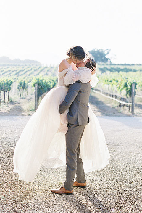  wedding at sunstone winery with romantic details and the groom in a café brown suit and the bride in a flowing ballgown with billowing sleeves