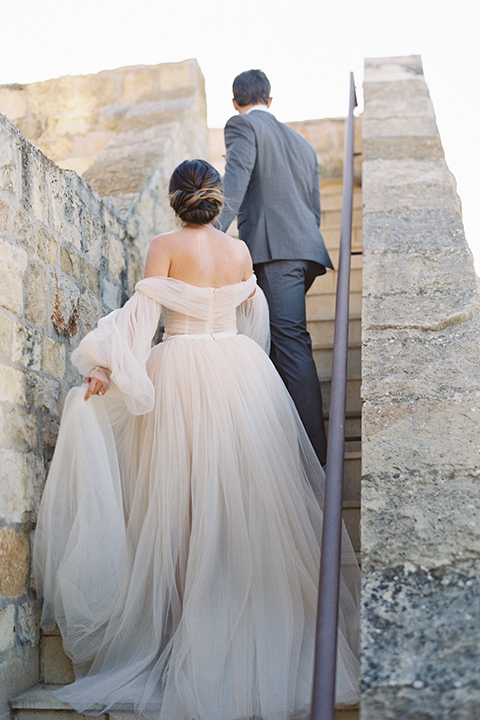  wedding at sunstone winery with romantic details and the groom in a café brown suit and the bride in a flowing ballgown with billowing sleeves 