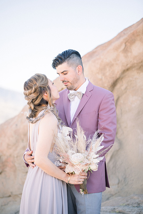  bride in a soft lilac colored gown for a dessert elopement and the groom in a rose pink suit and grey pants