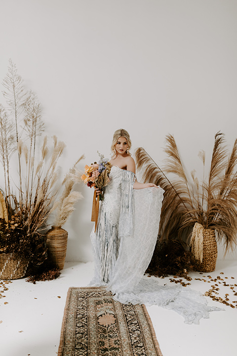  boho wedding with the ceremony inside and the reception on the cliffs overlooking the ocean and the bride in a finged gown and the groom in a tan suit 