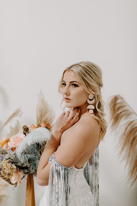  boho wedding with the ceremony inside and the reception on the cliffs overlooking the ocean and the bride in a finged gown and the groom in a tan suit 