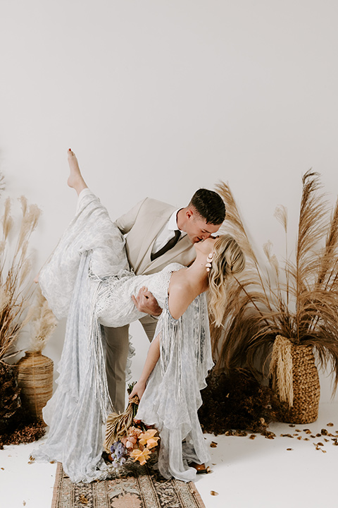  boho wedding with the ceremony inside and the reception on the cliffs overlooking the ocean and the bride in a finged gown and the groom in a tan suit 