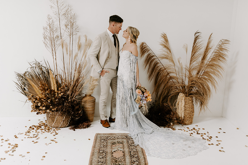  boho wedding with the ceremony inside and the reception on the cliffs overlooking the ocean and the bride in a finged gown and the groom in a tan suit 