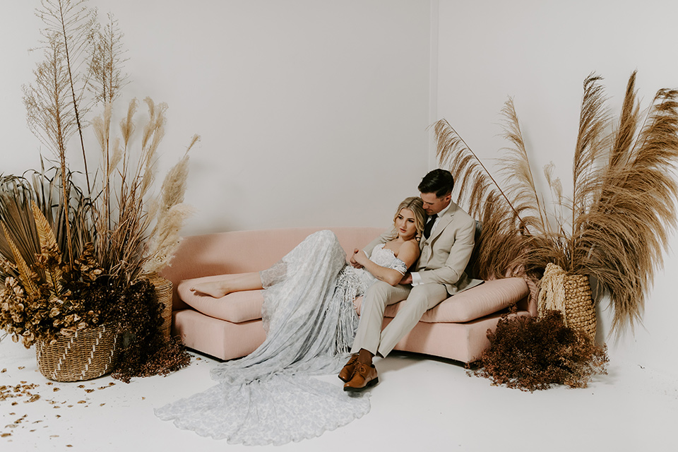  boho wedding with the ceremony inside and the reception on the cliffs overlooking the ocean and the bride in a finged gown and the groom in a tan suit 