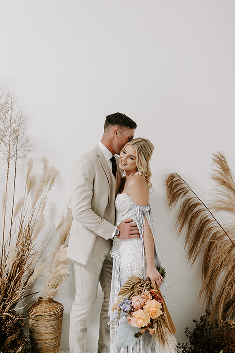  boho wedding with the ceremony inside and the reception on the cliffs overlooking the ocean and the bride in a finged gown and the groom in a tan suit 