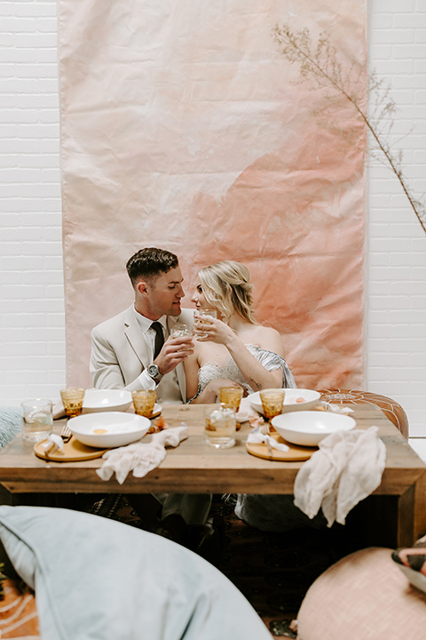  boho wedding with the ceremony inside and the reception on the cliffs overlooking the ocean and the bride in a finged gown and the groom in a tan suit 