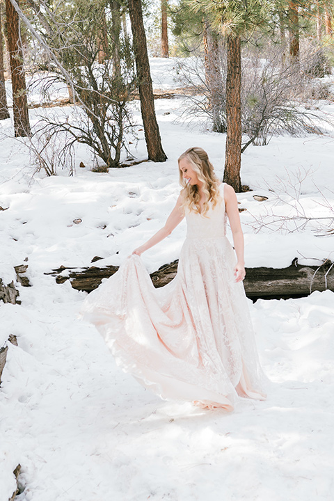  big bear elopement in the snow with the bride is a lace gown and the groom in a green suit – bride twirling