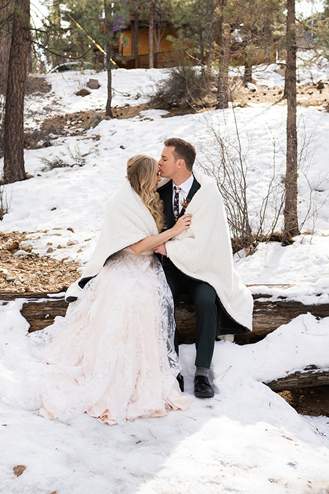  big bear elopement in the snow with the bride is a lace gown and the groom in a green suit – couple in the snow