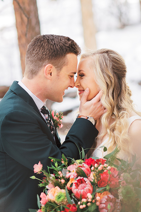  big bear elopement in the snow with the bride is a lace gown and the groom in a green suit – couple kissing