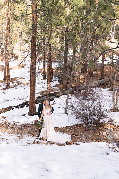  big bear elopement in the snow with the bride is a lace gown and the groom in a green suit – couple kissing