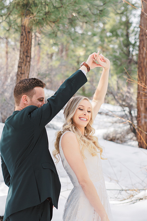  big bear elopement in the snow with the bride is a lace gown and the groom in a green suit – couple kissing 