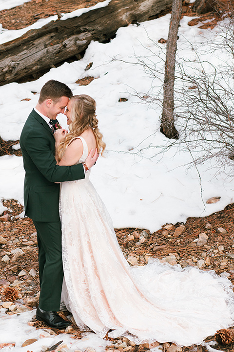  big bear elopement in the snow with the bride is a lace gown and the groom in a green suit – couple kissing 