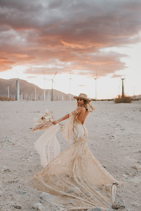  eloping in the desert with a bohemian vibe – bride in a lace gown and the groom in a caramel brown suit -bride in her gown dancing