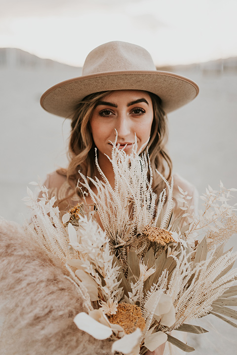  eloping in the desert with a bohemian vibe – bride in a lace gown and the groom in a caramel brown suit -bride in her gown dancing 