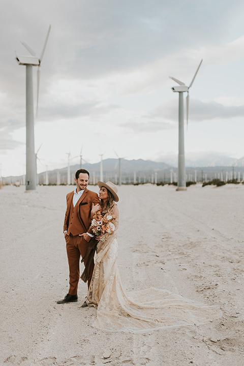  eloping in the desert with a bohemian vibe – bride in a lace gown and the groom in a caramel brown suit -couple embracing